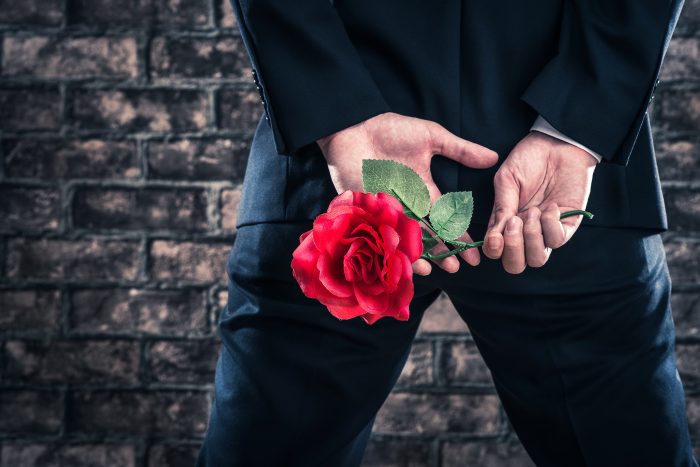 バラの花を持っているスーツの男性