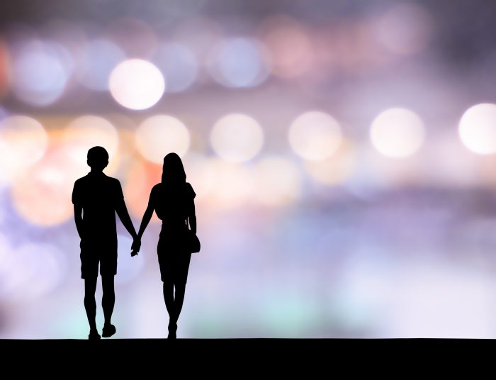 Happy young couple walking on city street and neon background
