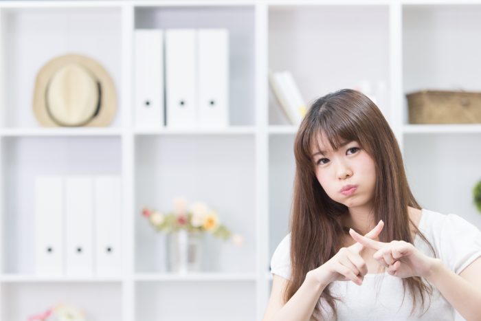 指でバツをつくるかわいい女性