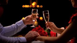 Couple holding glasses with champagne, male stroking lady hand tenderly, romance