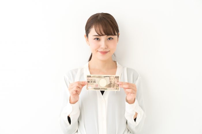 お金を両手で持つ笑顔の女性