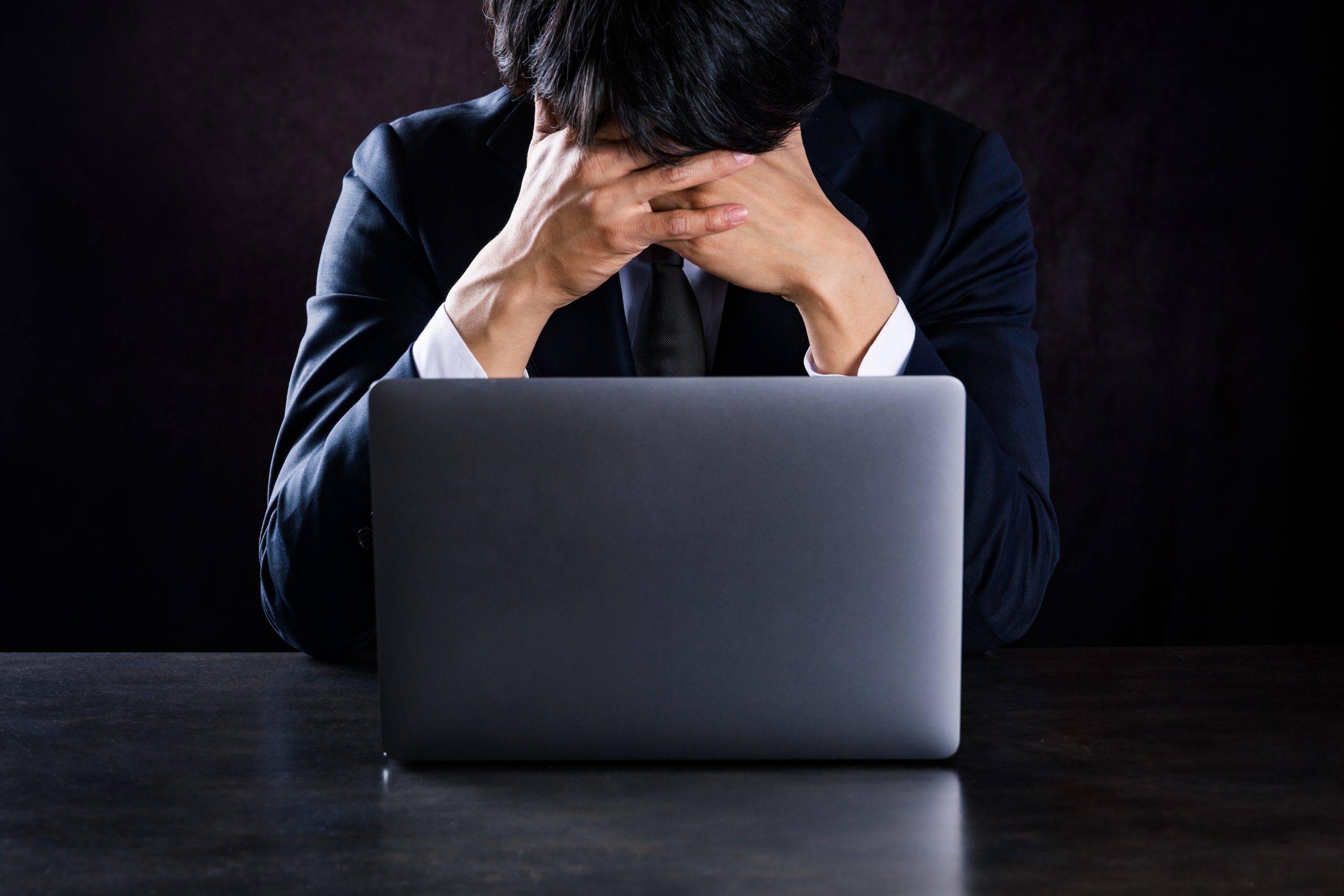 ノートパソコンの前で疲労した男性