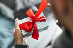 Man holding gift with red ribbon