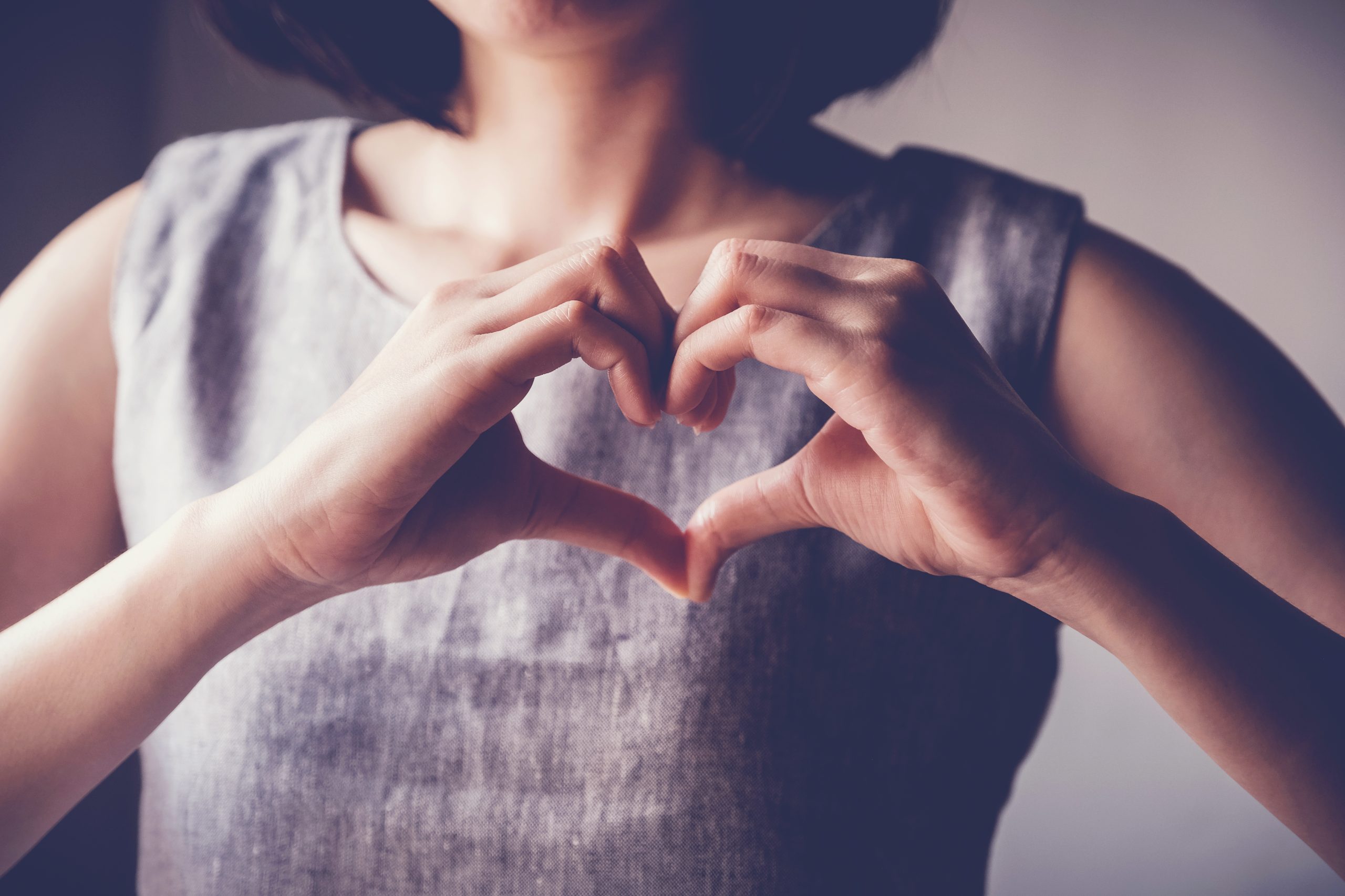 young woman making her hands in heart shape, heart health insurance, social responsibility, donation charity, world heart day, appreciation, world mental health day concept