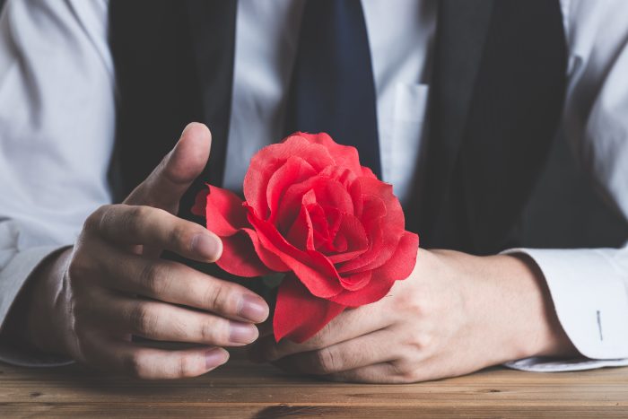 赤いバラの花を持っている男性
